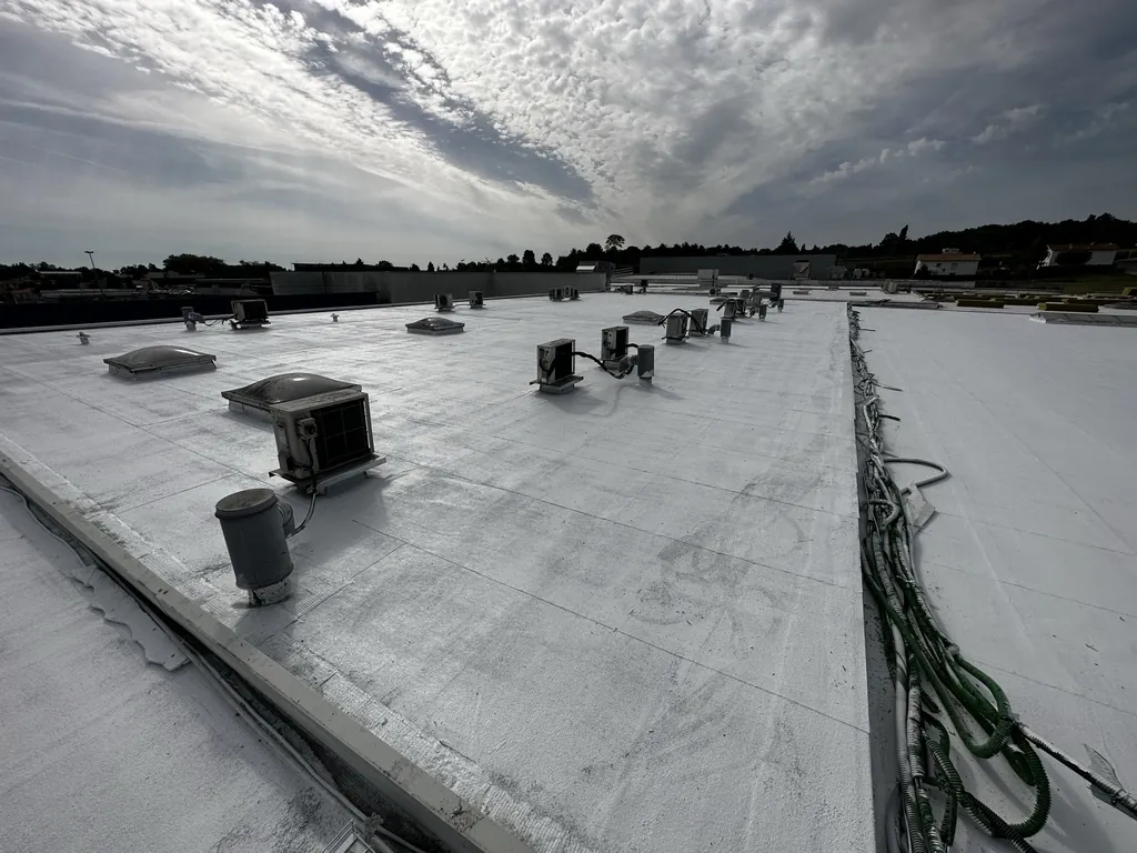 Toiture-terrasse recouverte de blanc, avec ses équipements techniques, sous un ciel nuageux